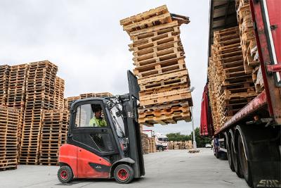 A man moving wood pallets using a forklift.