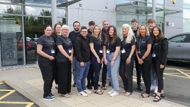 A group of various staff members from AbacusBean stand smiling outside their offices